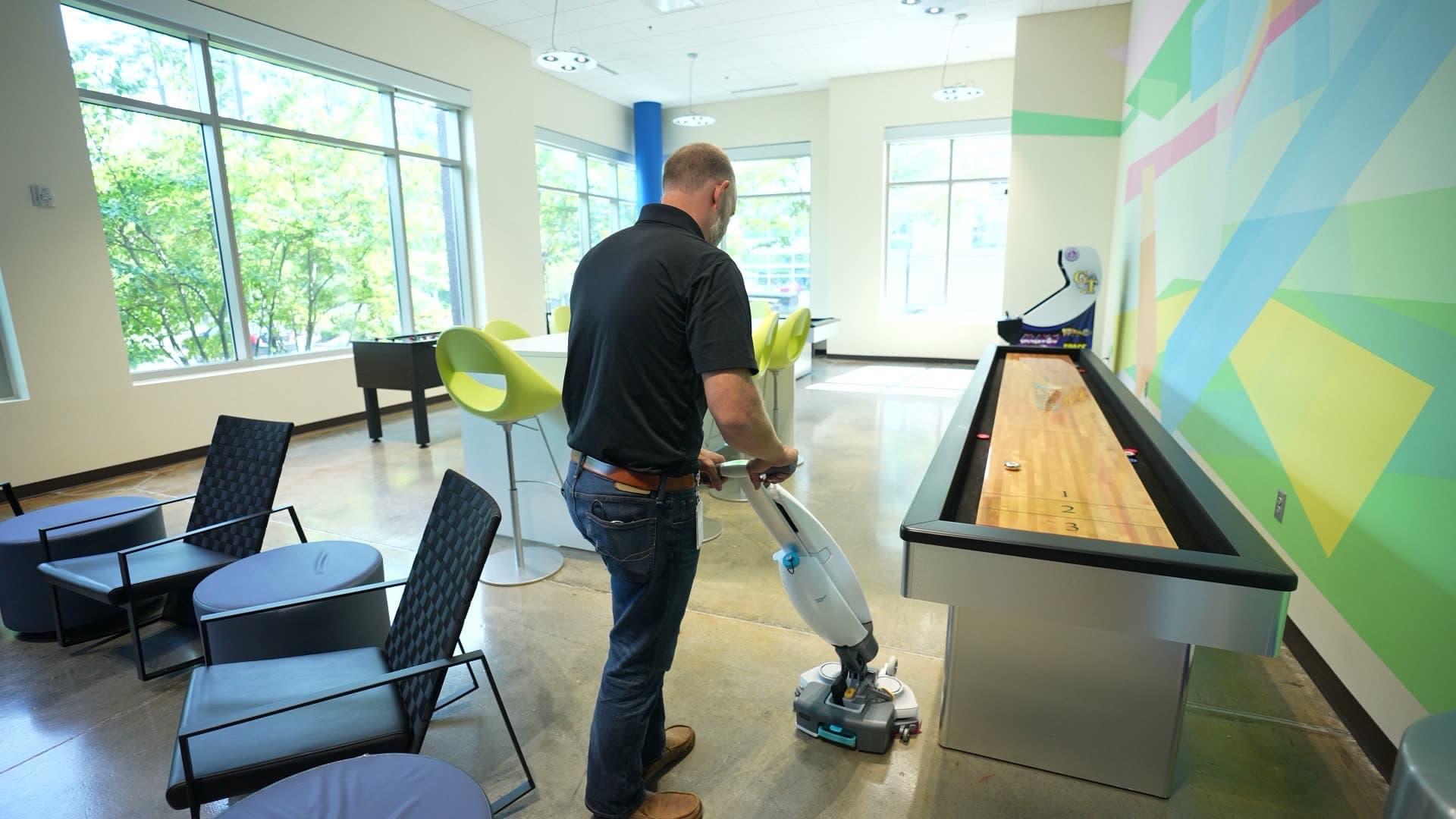 MFS technician operating floor buffer in a large studio space